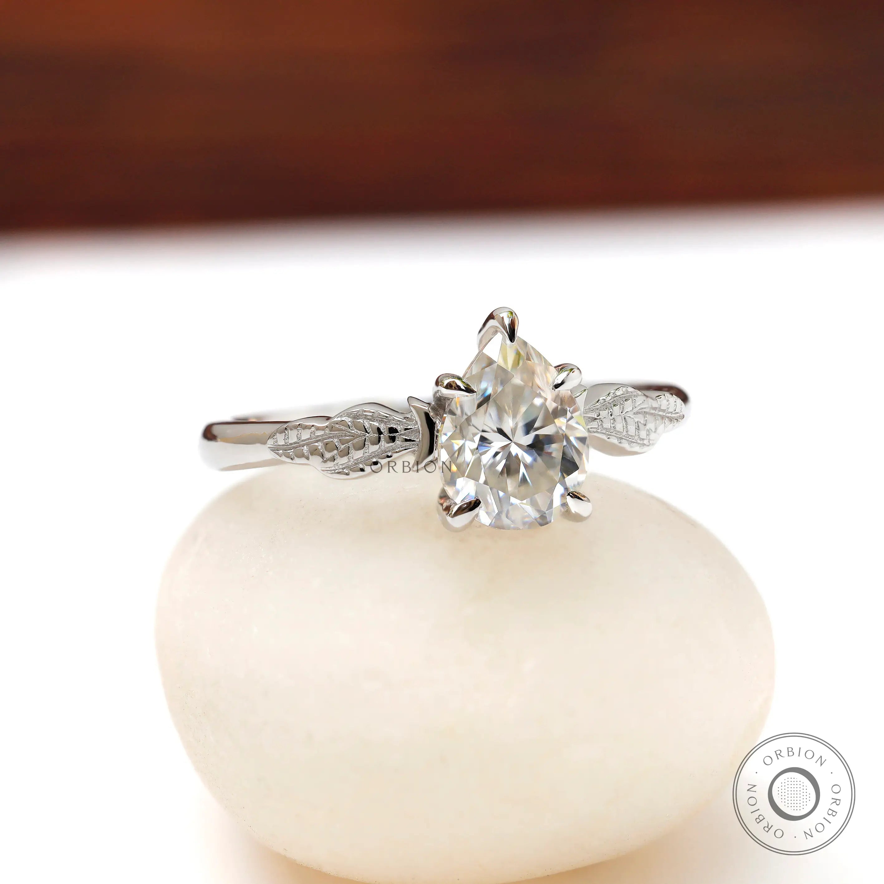 Angled view of pear Moissanite engagement ring with leaf details