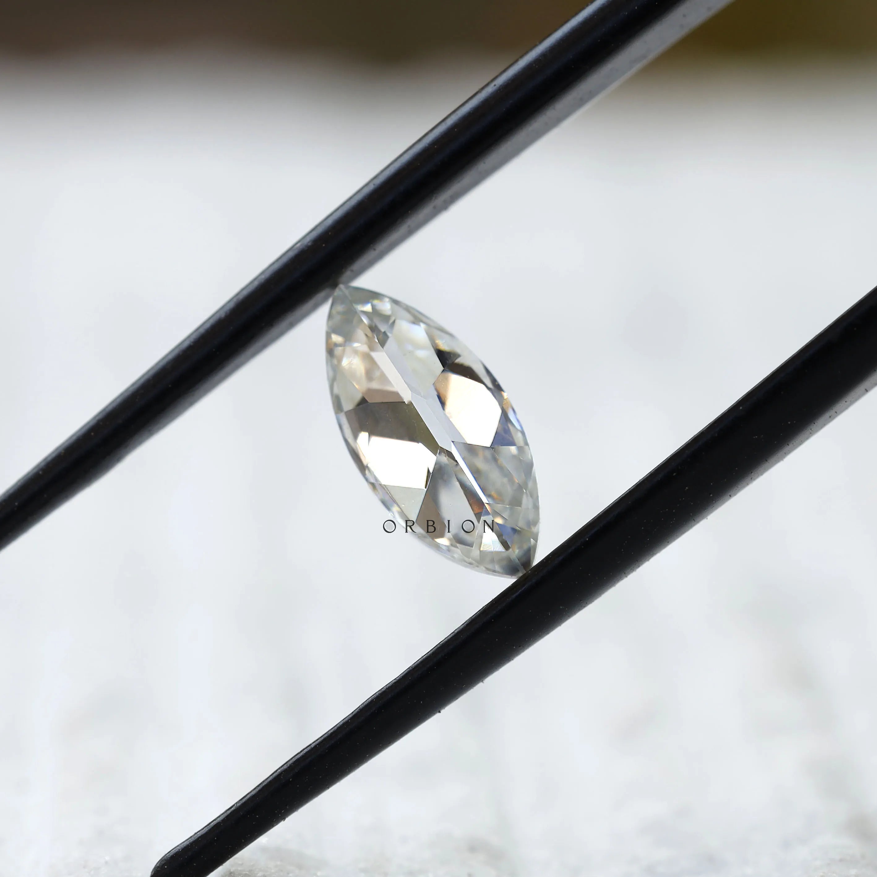 Close-up of marquise loose moissanite held in tweezers