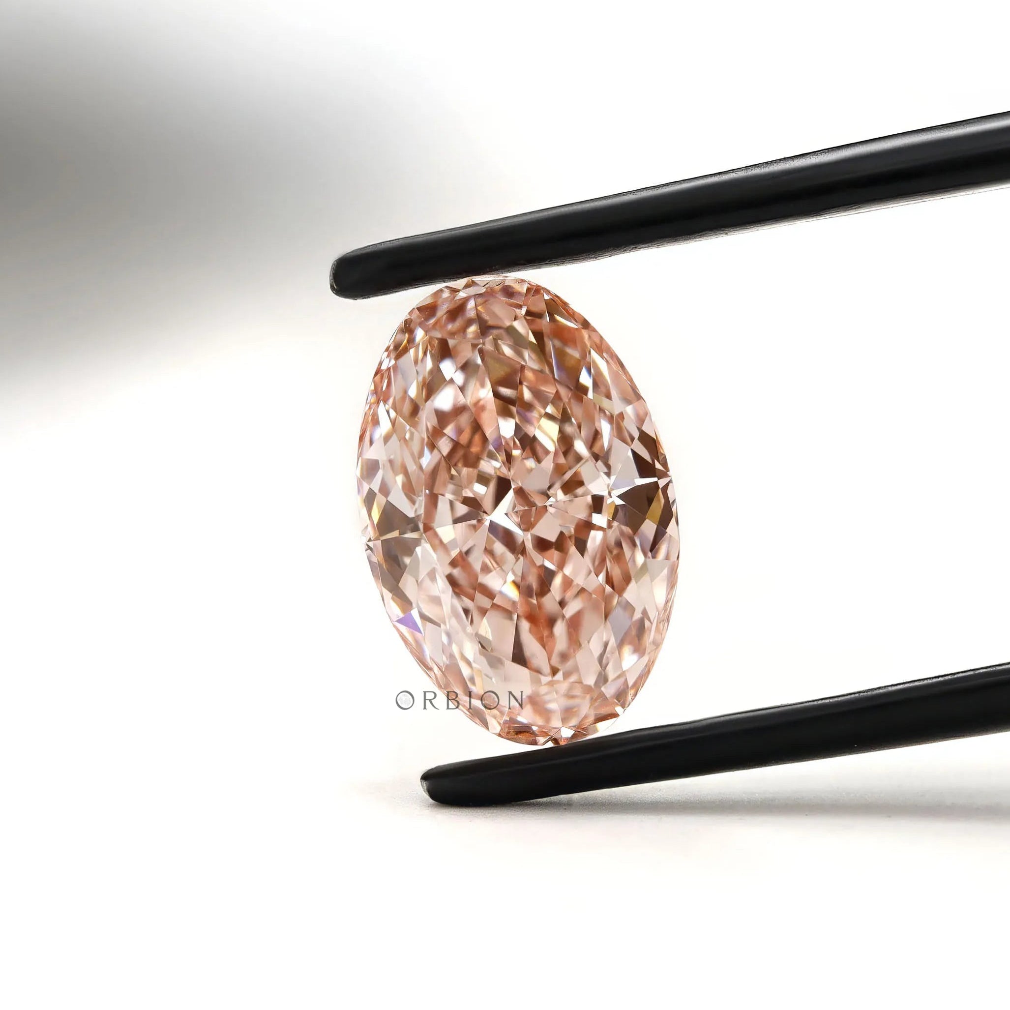 Intense pink oval lab grown diamond held in black tweezers