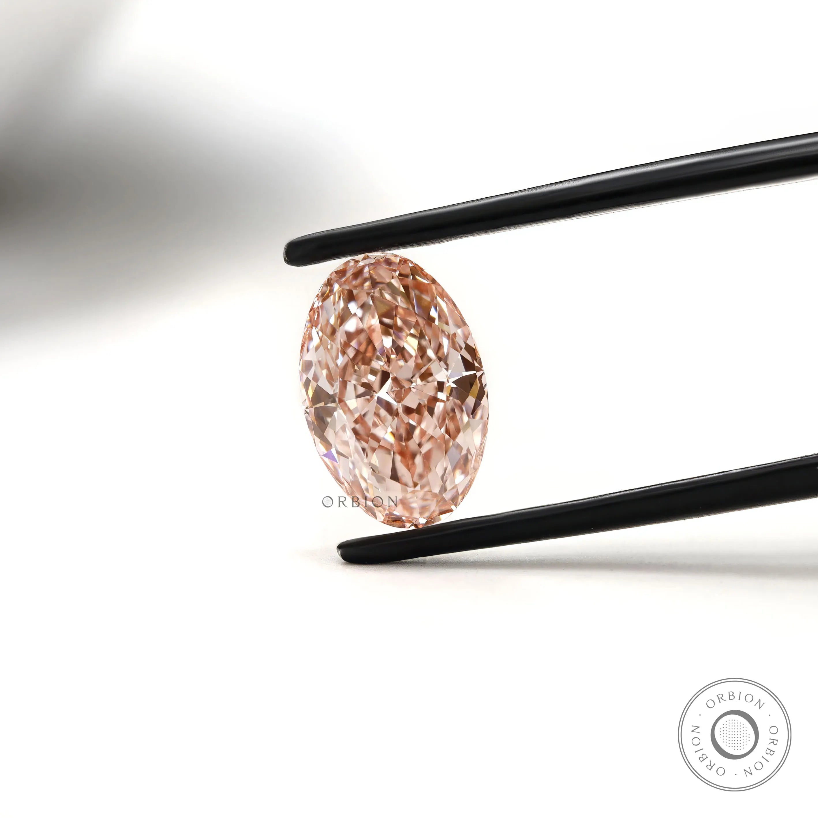 Intense pink oval lab grown diamond held in black tweezers