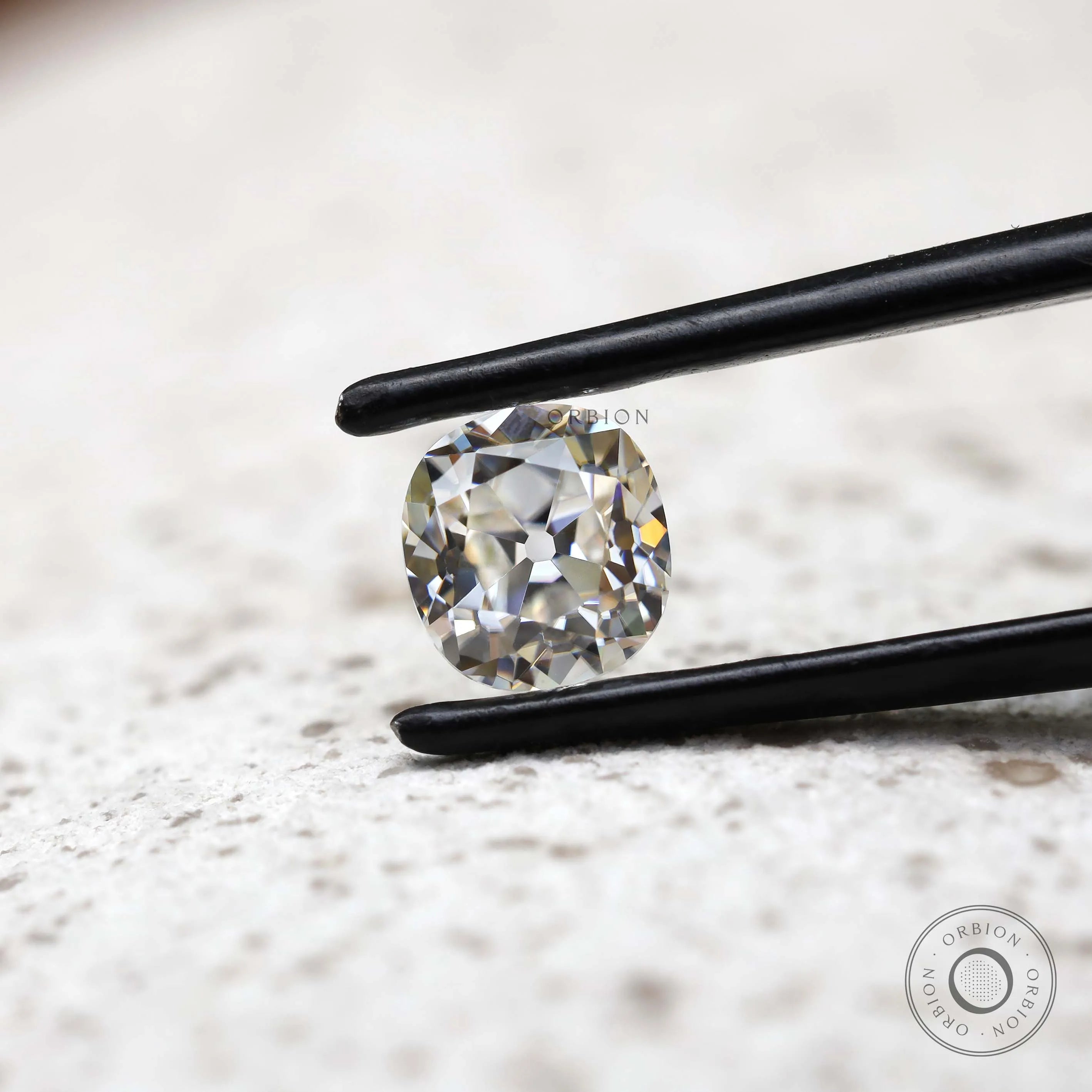 DEF elongated cushion loose moissanite shown in black tweezers