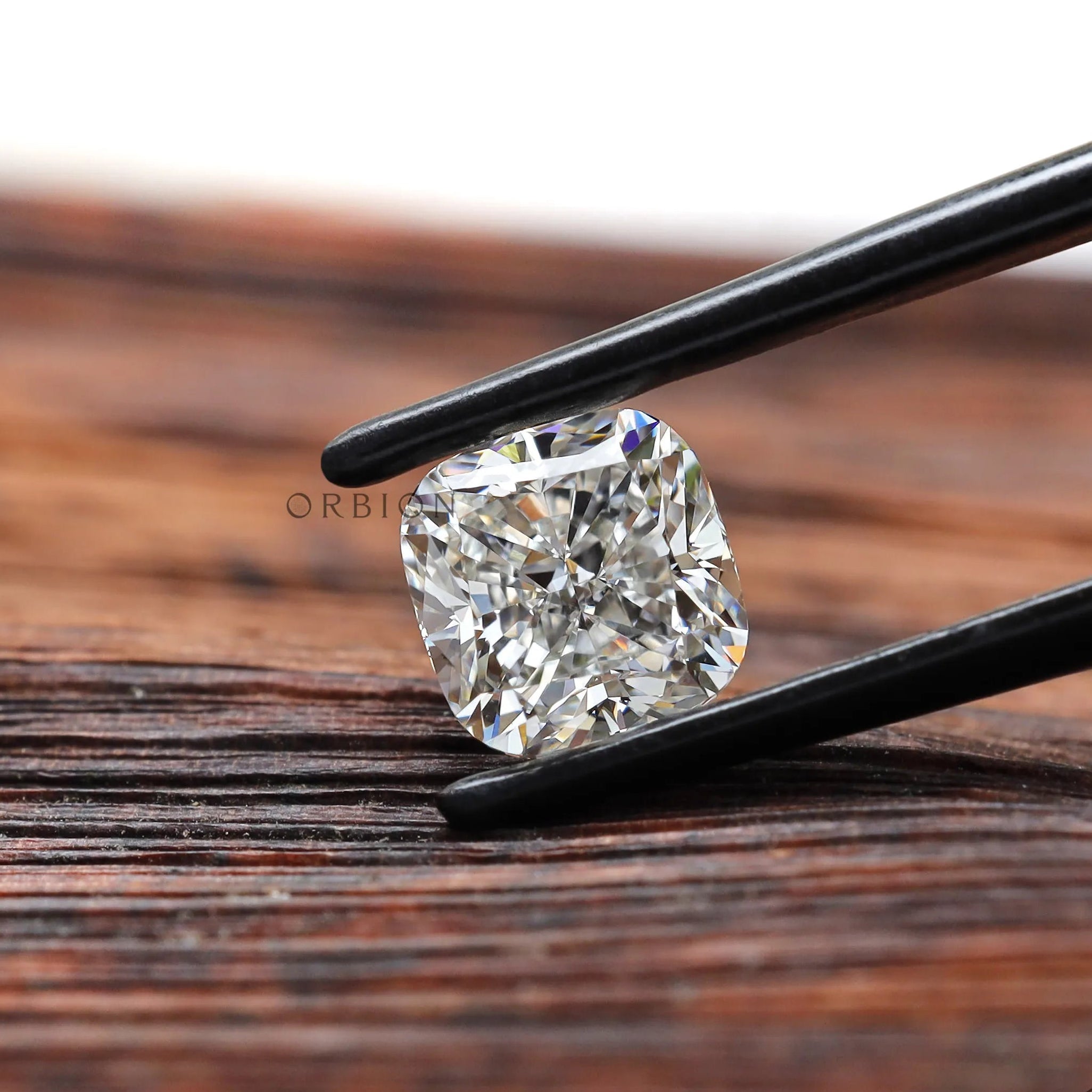 Close view of cushion lab diamond in black tweezers