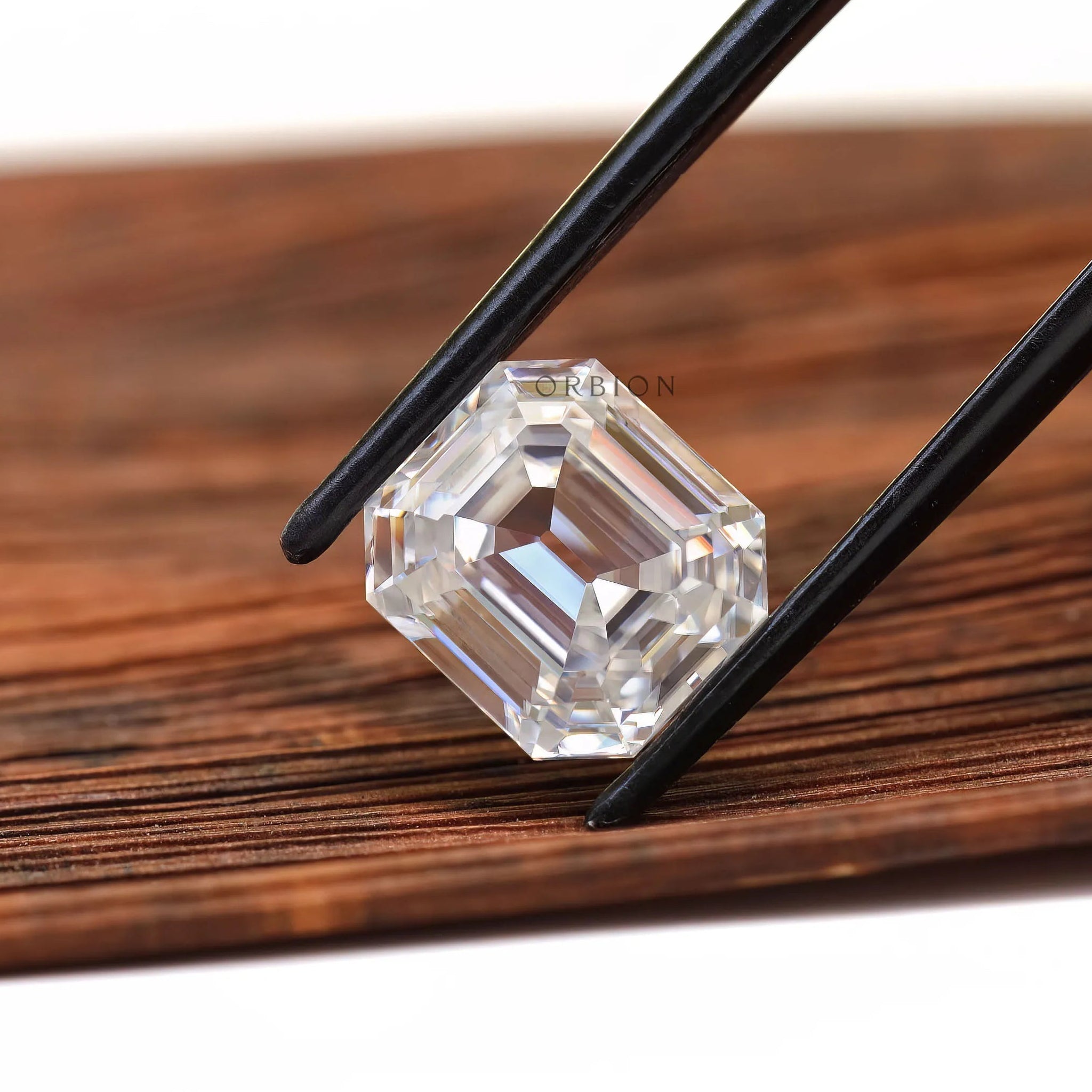 Emerald step cut loose moissanite in angled wooden display