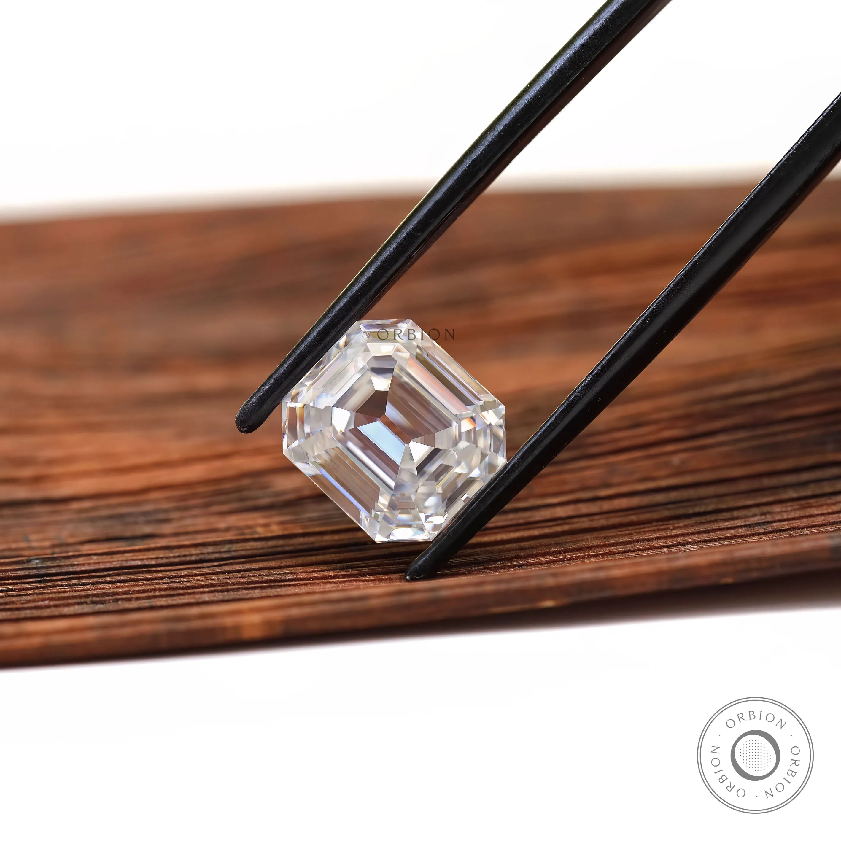 Emerald step cut loose moissanite in angled wooden display