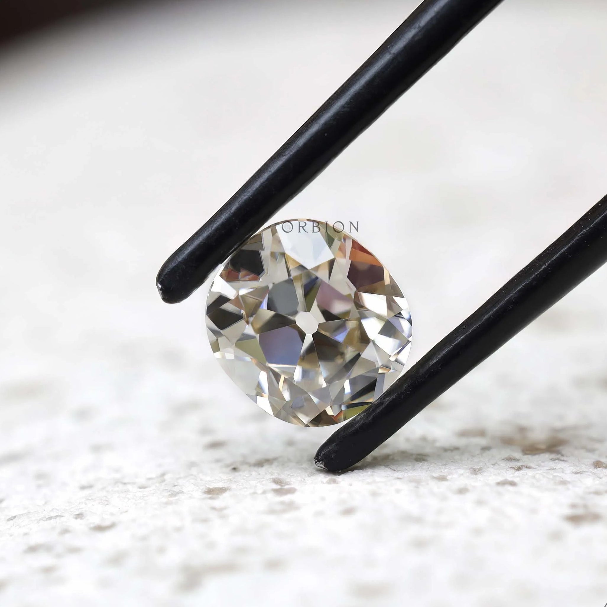GHI elongated cushion moissanite held in black tweezers close-up