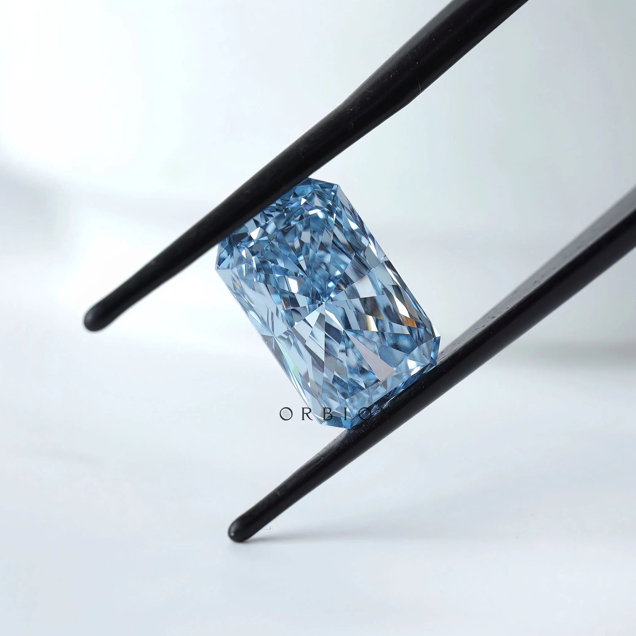 Angled view radiant blue loose lab diamond in tweezers
