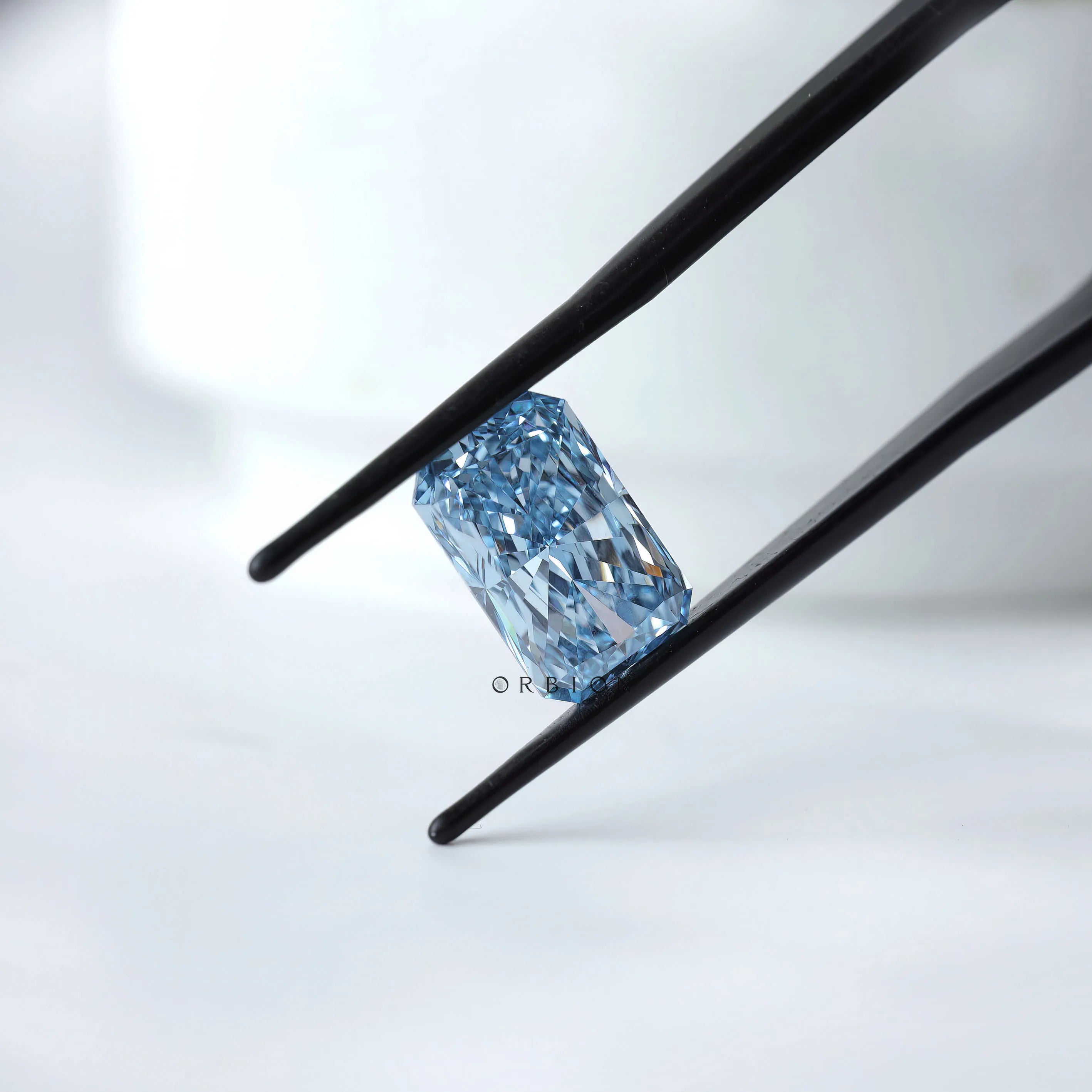 Angled view radiant blue loose lab diamond in tweezers