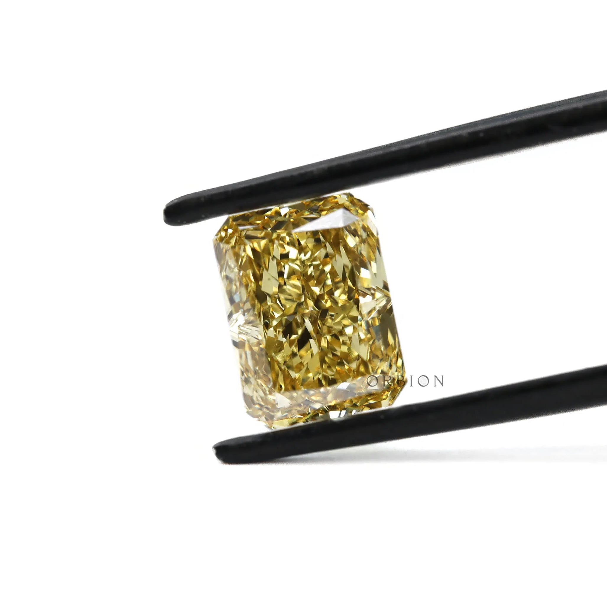 Fancy yellow radiant lab diamond held in black tweezers close-up