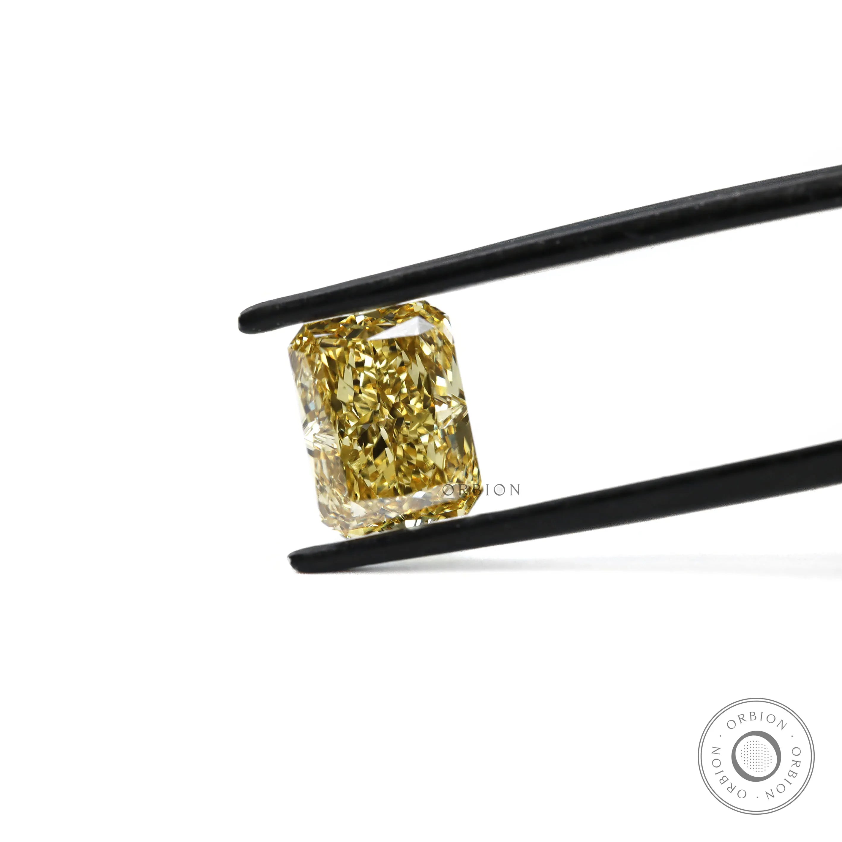 Fancy yellow radiant lab diamond held in black tweezers close-up