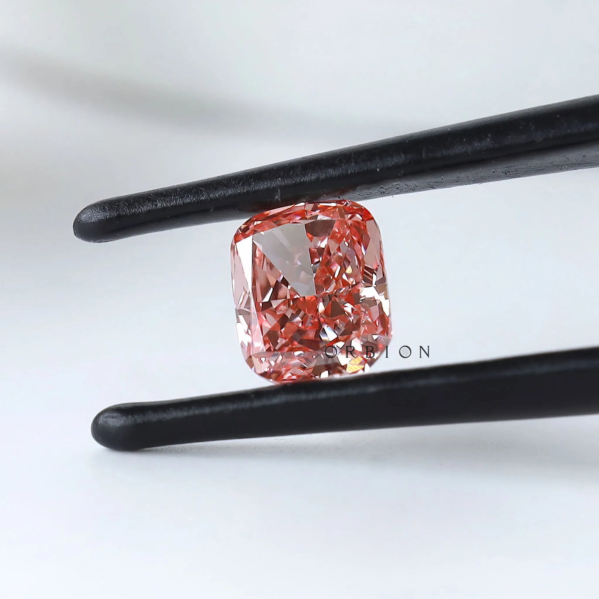 Cushion modified brilliant vivid pink lab diamond angled in tweezers