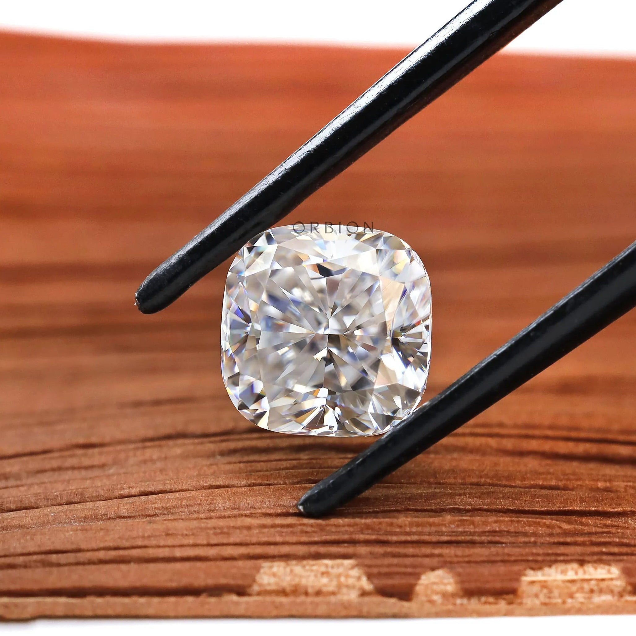 Square cushion loose moissanite in black tweezers close-up
