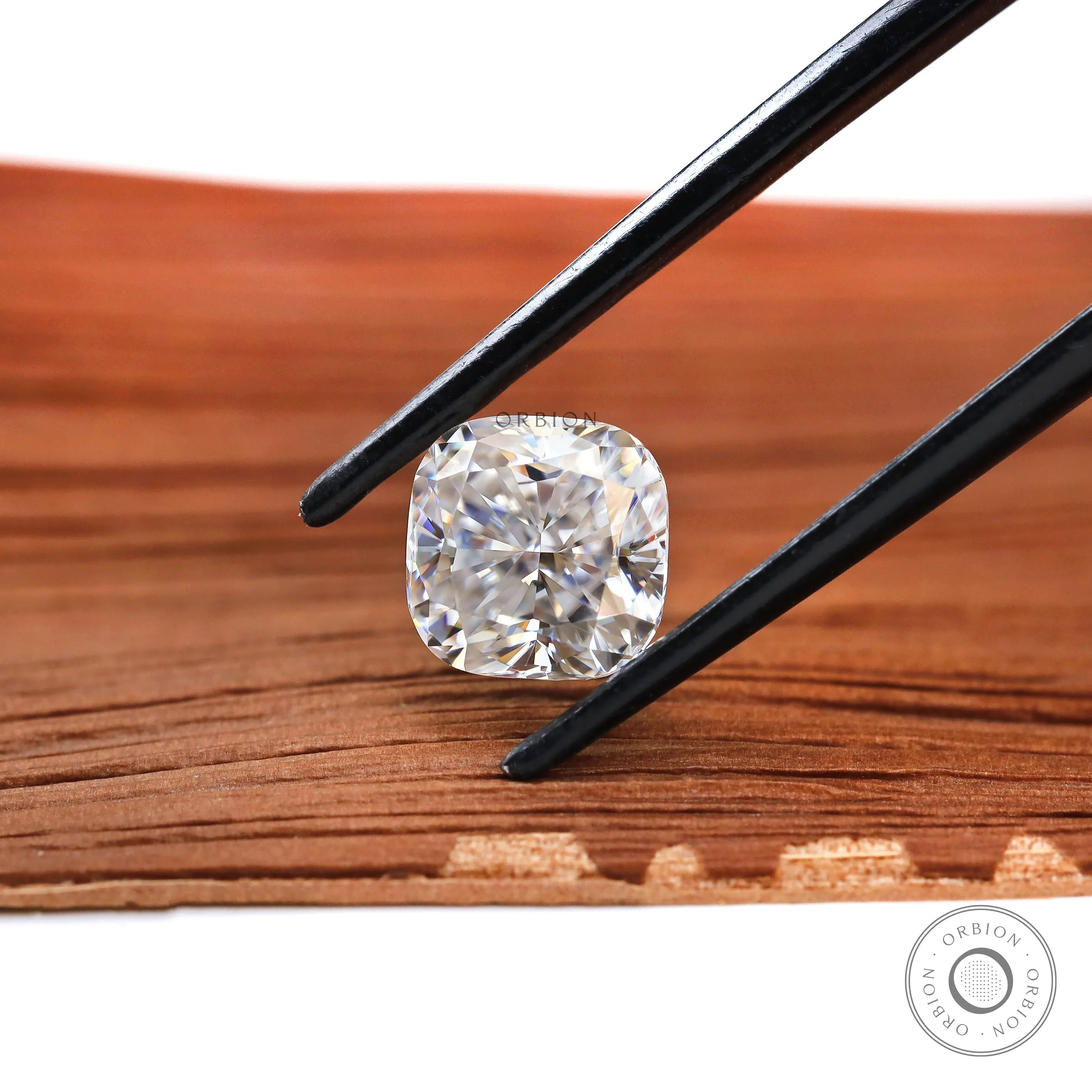 Square cushion loose moissanite in black tweezers close-up