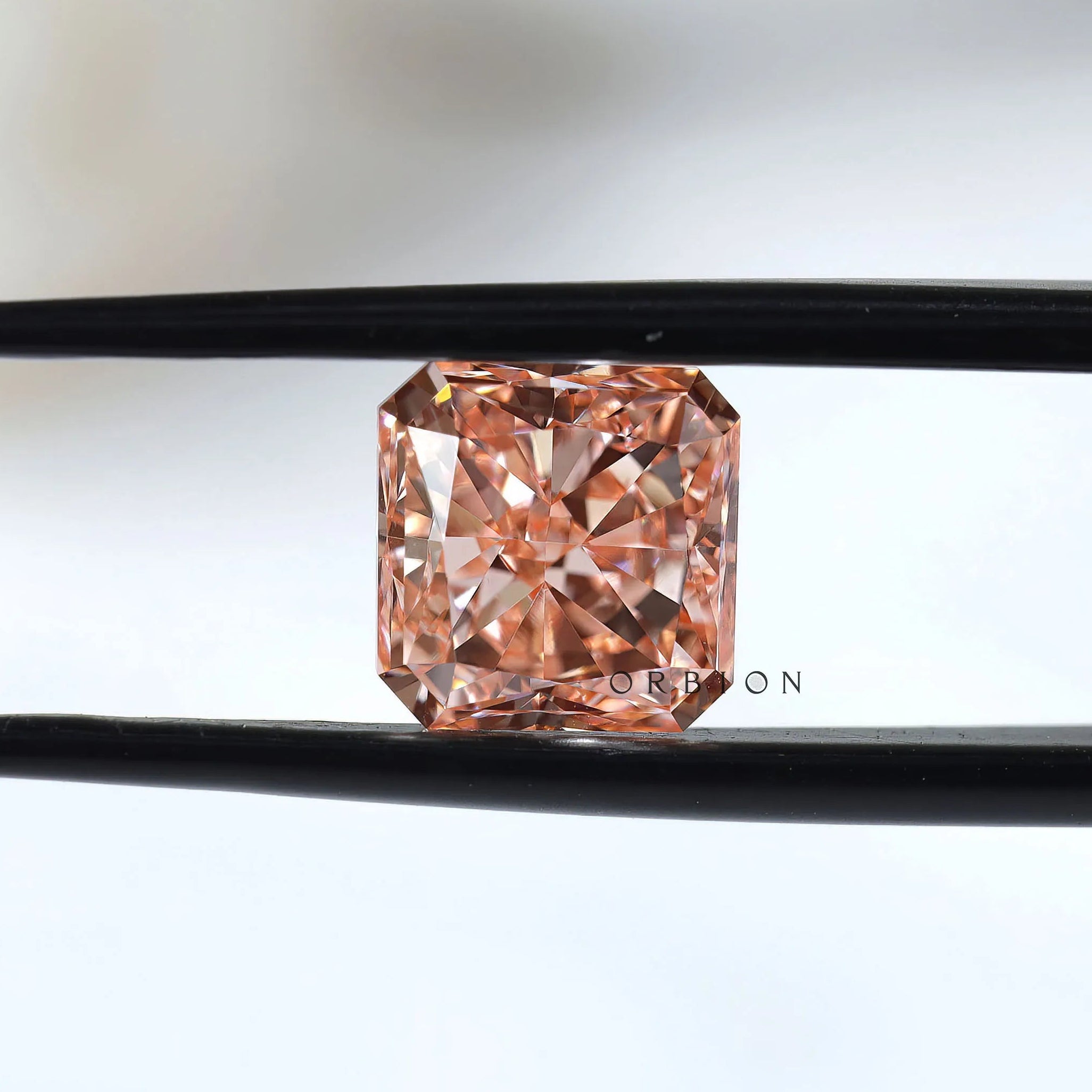 Fancy vivid pink radiant diamond held between black tweezers