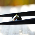 Black pear moissanite stone in tweezers showcasing detail