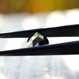 Black pear moissanite stone in tweezers showcasing detail
