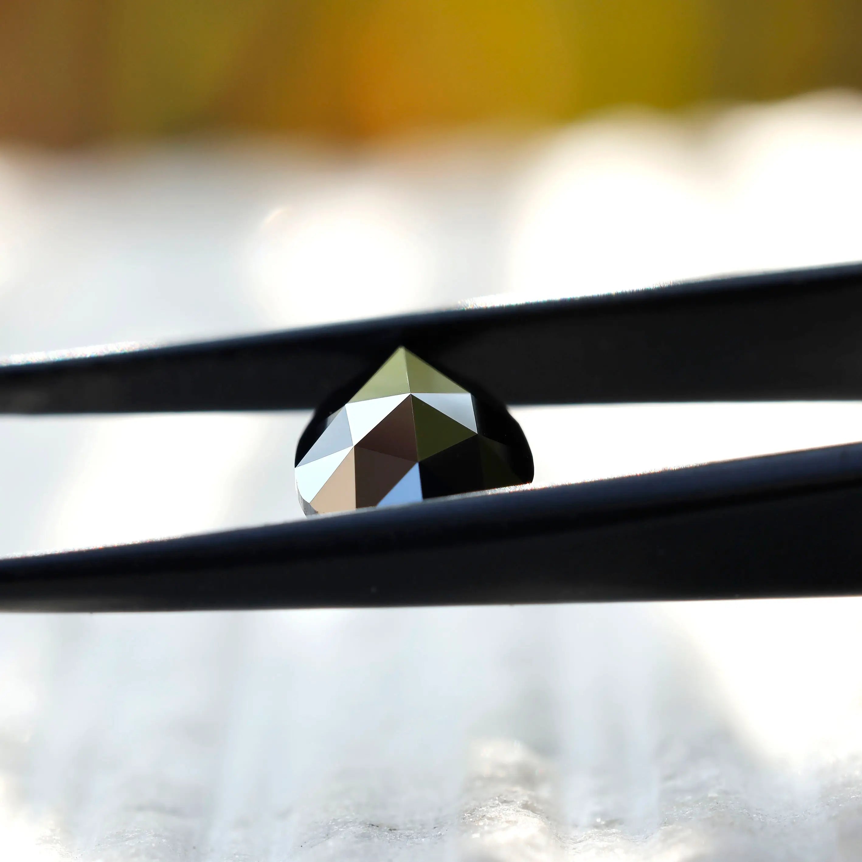 Black pear moissanite stone in tweezers showcasing detail