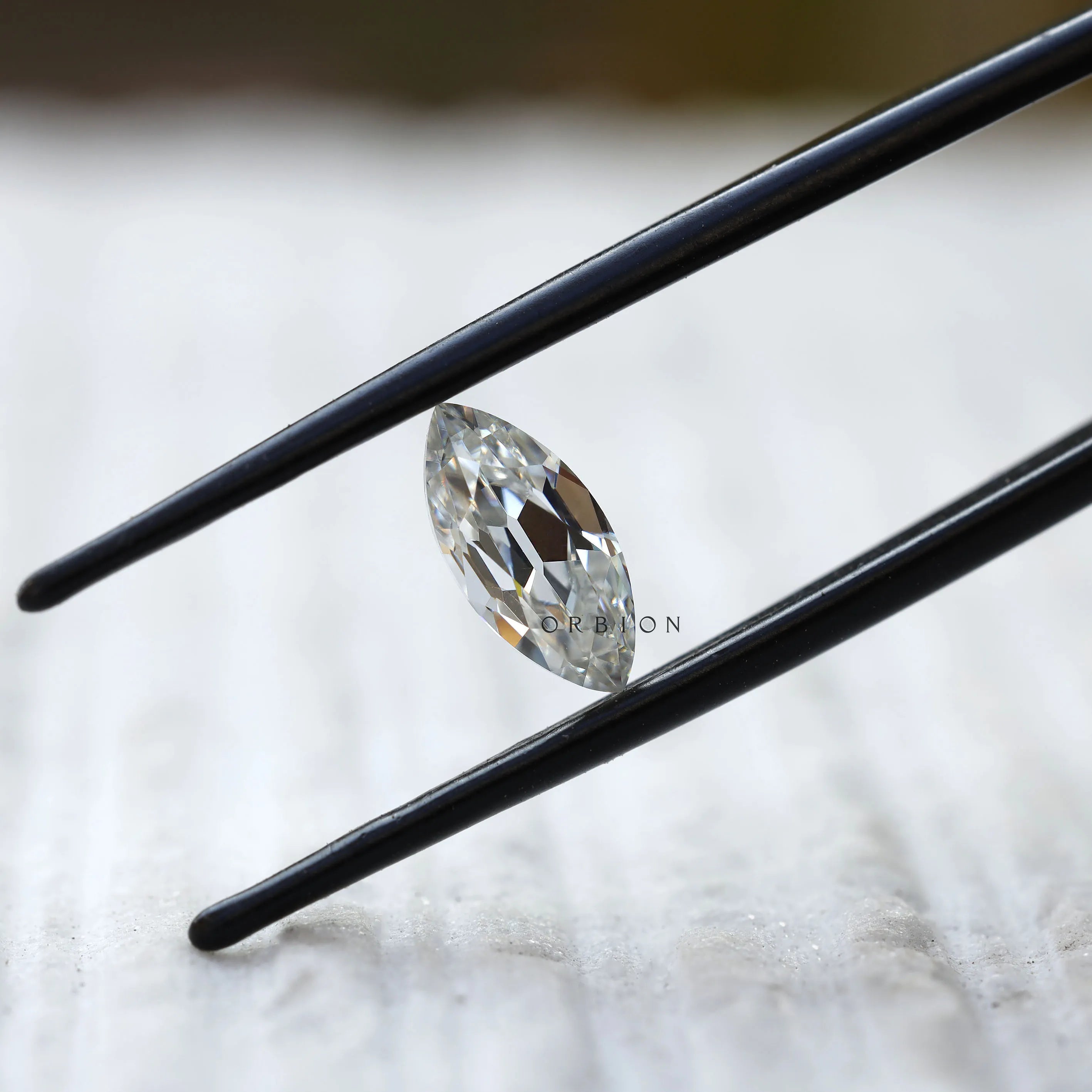 1.26 ct marquise cut moissanite in black tweezers