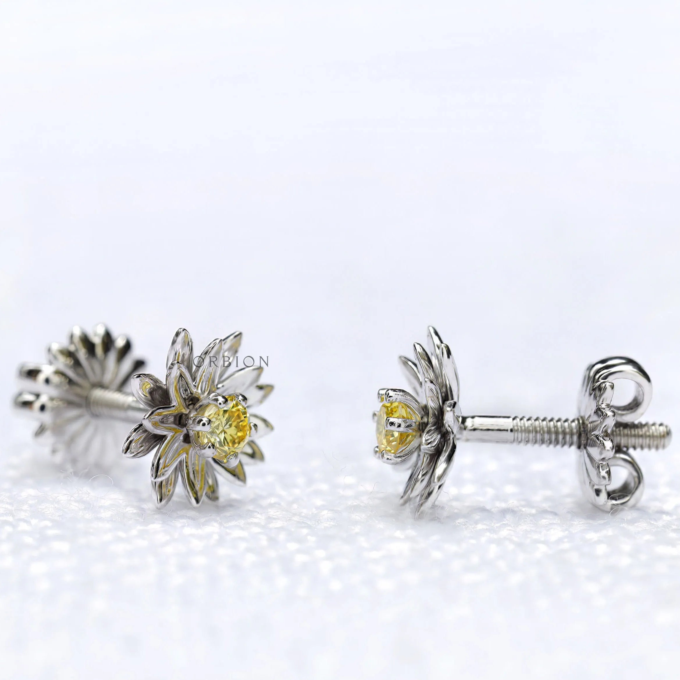 Close-up of lotus flower stud earrings with yellow diamond centerpiece