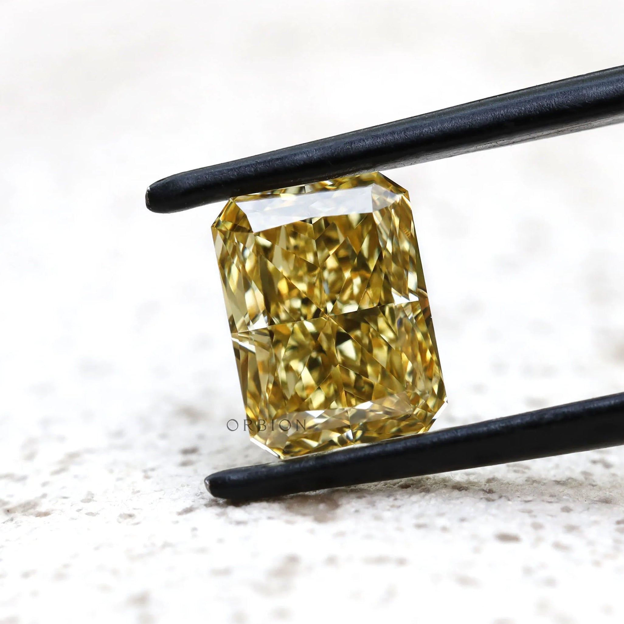Fancy yellow radiant lab diamond on light textured background