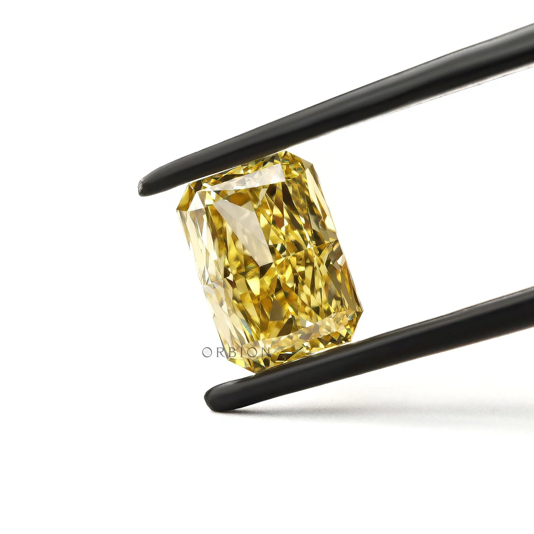Brilliant cut radiant yellow lab diamond angled in tweezers