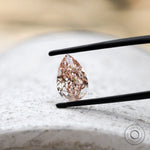 Fancy vivid pink pear diamond on light stone surface