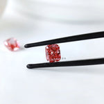 Front view of fancy vivid pink cushion diamond in tweezers