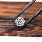 Angled round brilliant loose diamond held in black tweezers