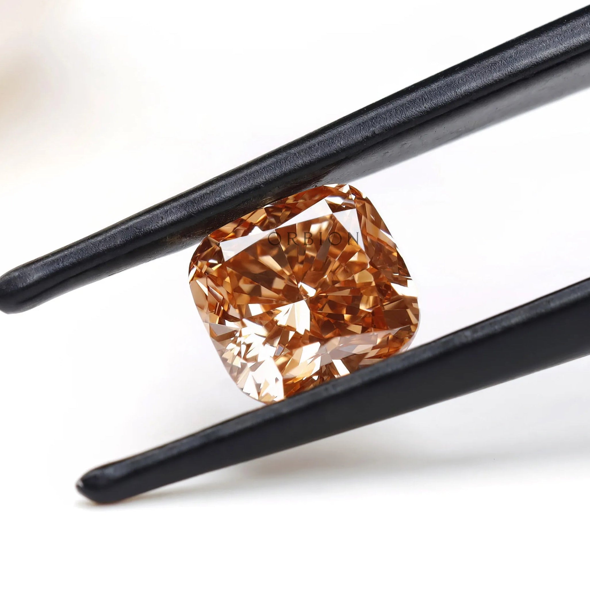 Angled view of fancy orange cushion lab diamond in tweezers