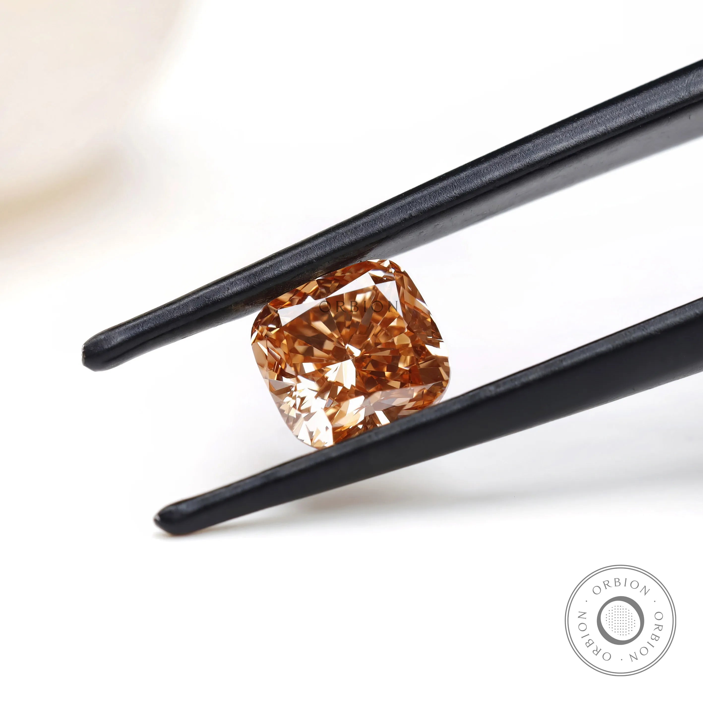 Angled view of fancy orange cushion lab diamond in tweezers