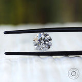 Round brilliant loose diamond angled between black tweezers