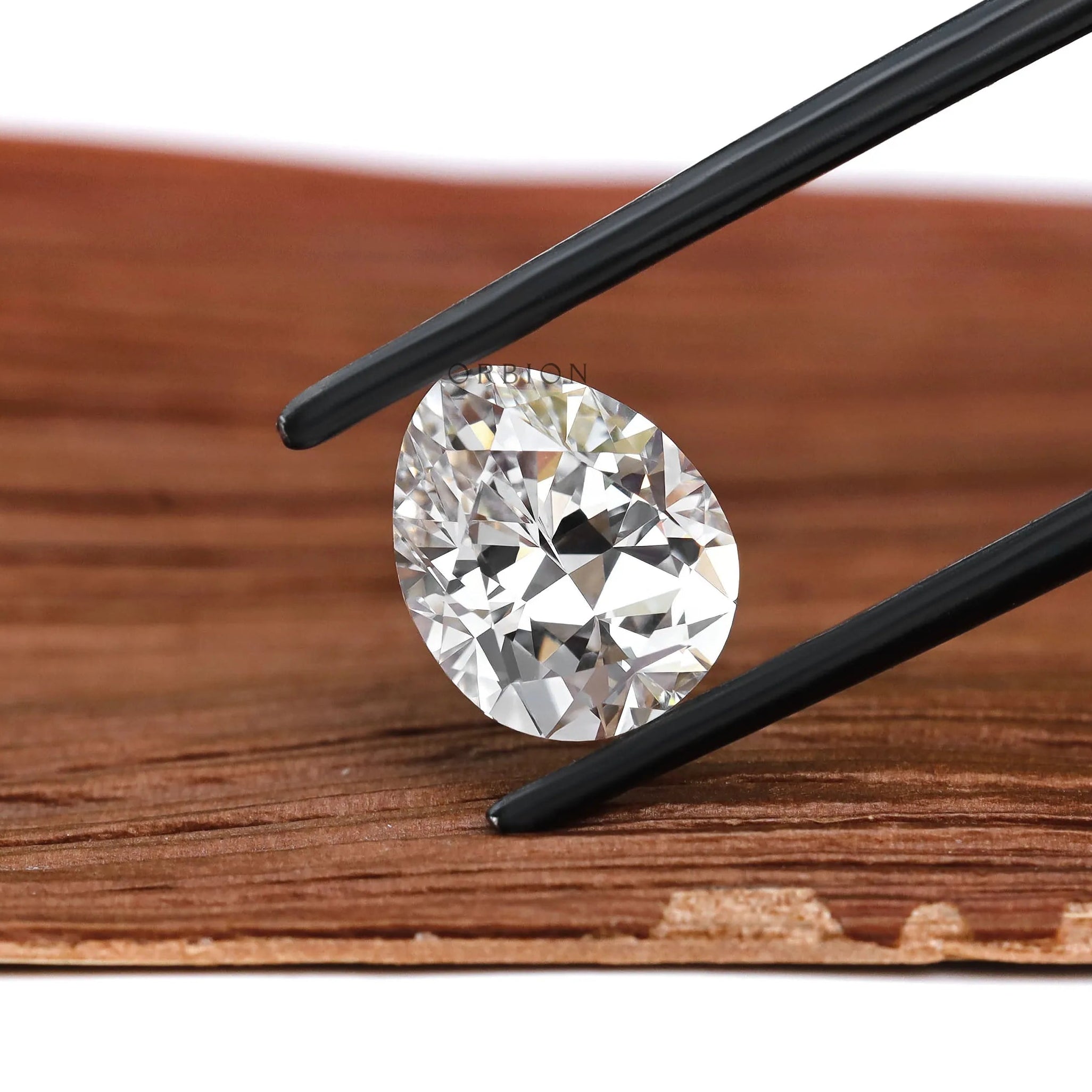 Pear shaped DEF lab diamond angled on warm wood background