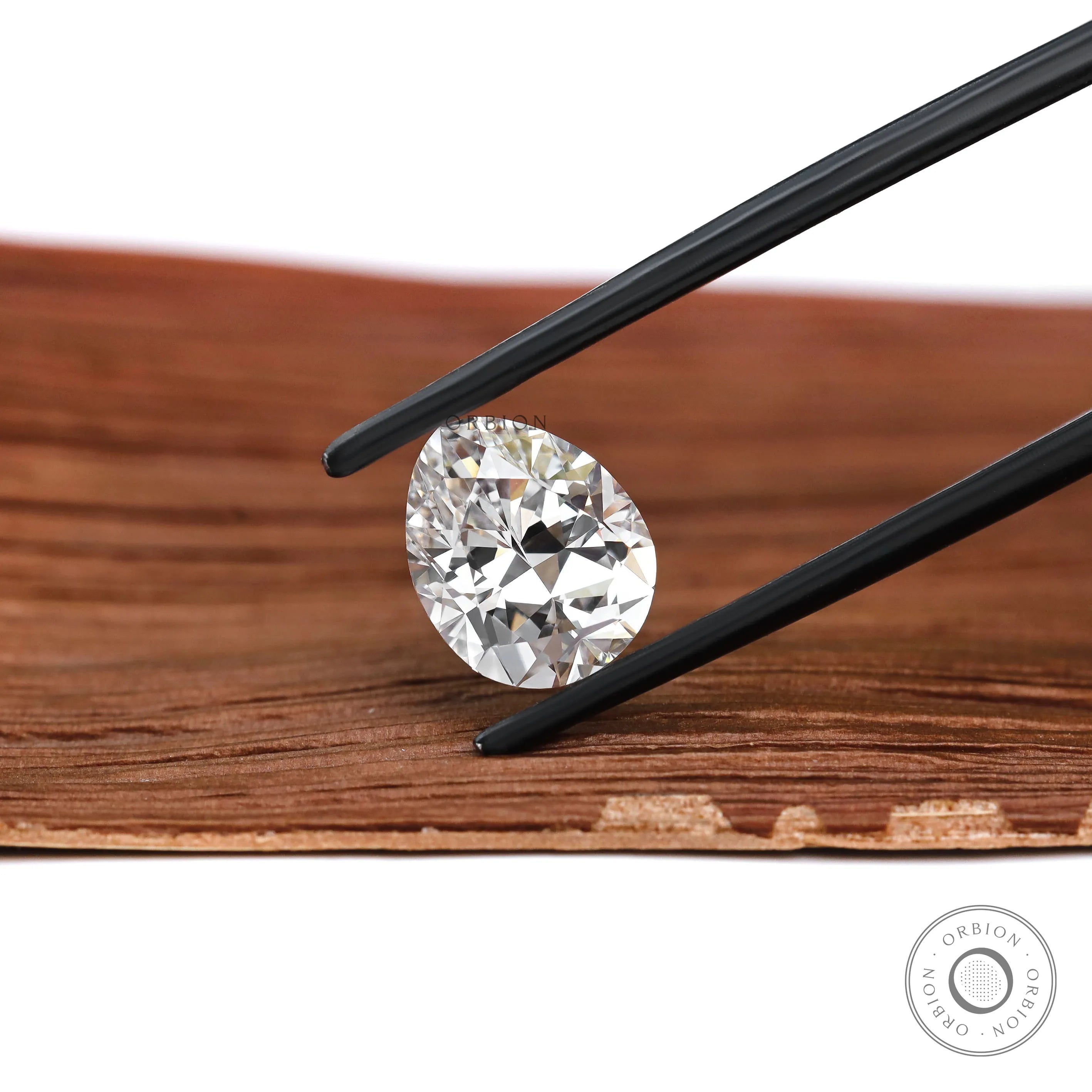 Pear shaped DEF lab diamond angled on warm wood background