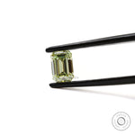 Fancy green emerald diamond held horizontally in tweezers