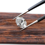 Loose oval brilliant lab diamond displayed over wooden surface