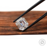 Step cut emerald moissanite shown diagonally in black tweezers