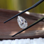 Side profile pear moissanite shown above wooden surface