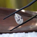 Side profile pear moissanite shown above wooden surface