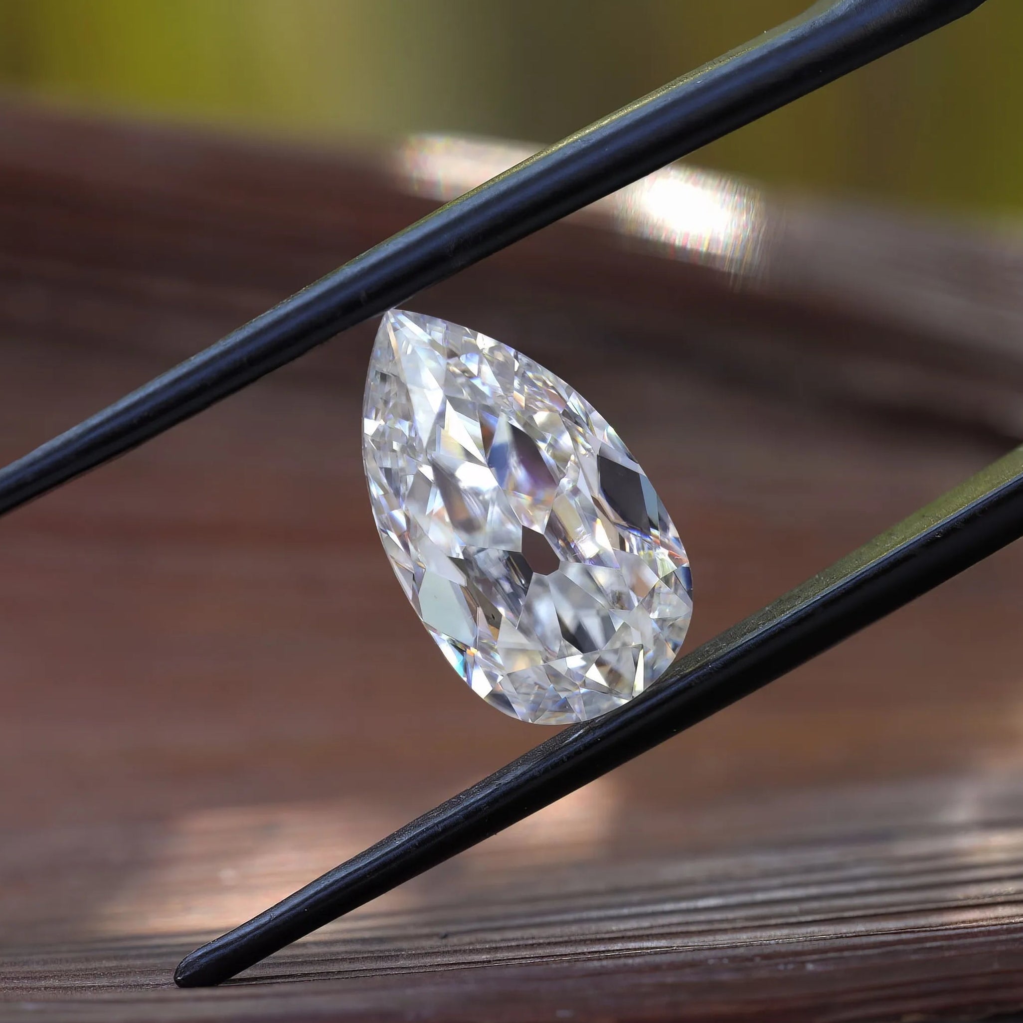 Side profile pear moissanite shown above wooden surface