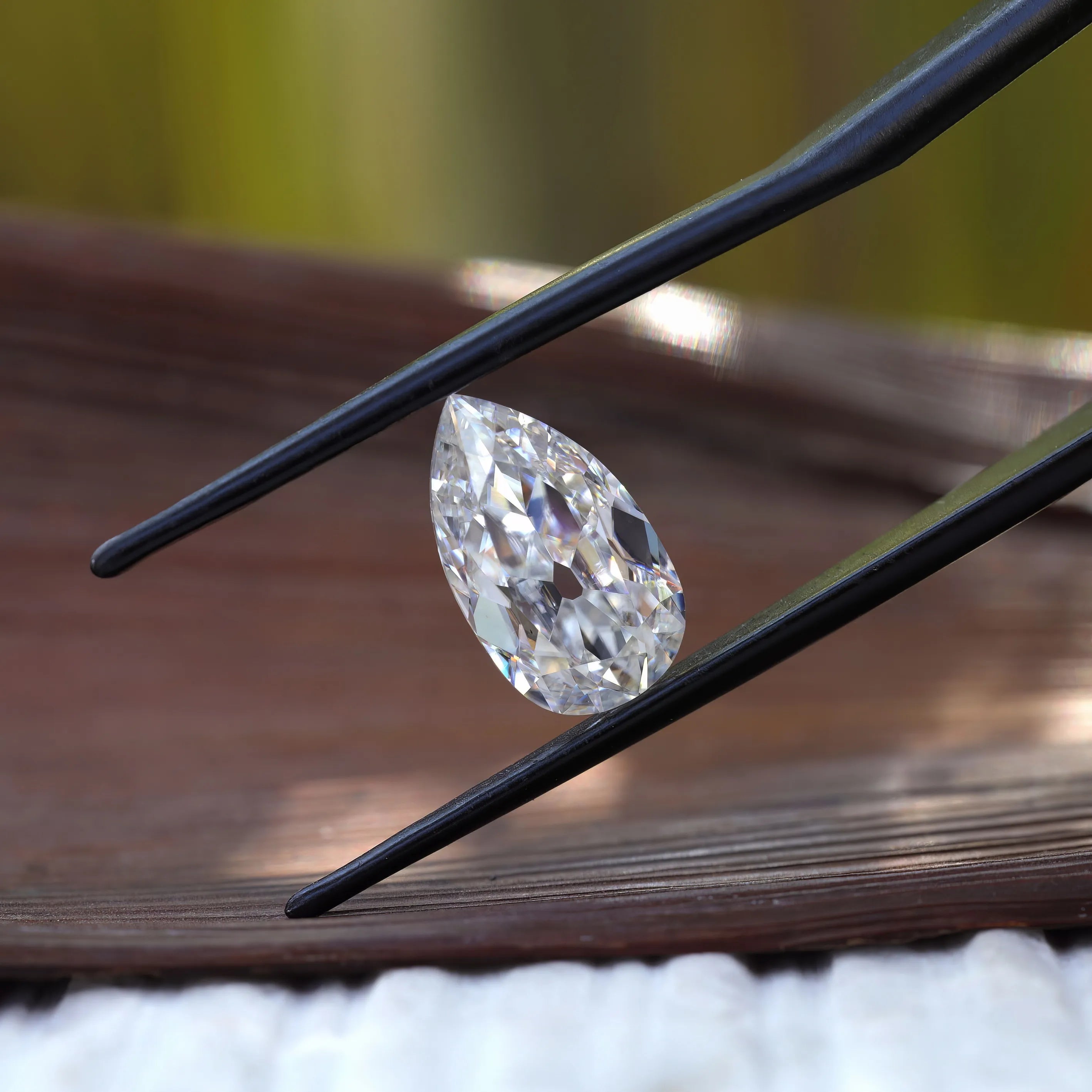 Side profile pear moissanite shown above wooden surface