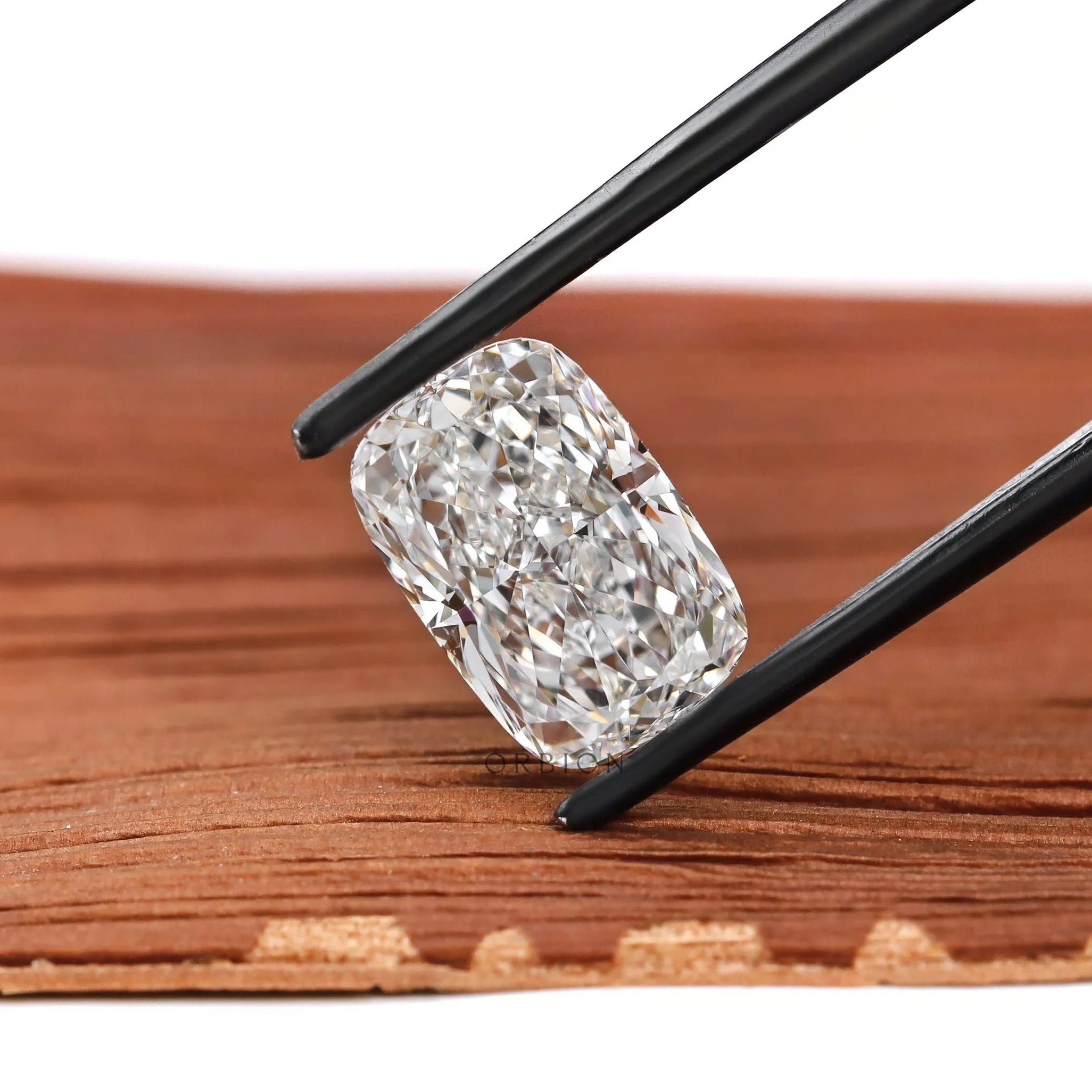 Angled elongated cushion brilliant cut lab diamond in black tweezers