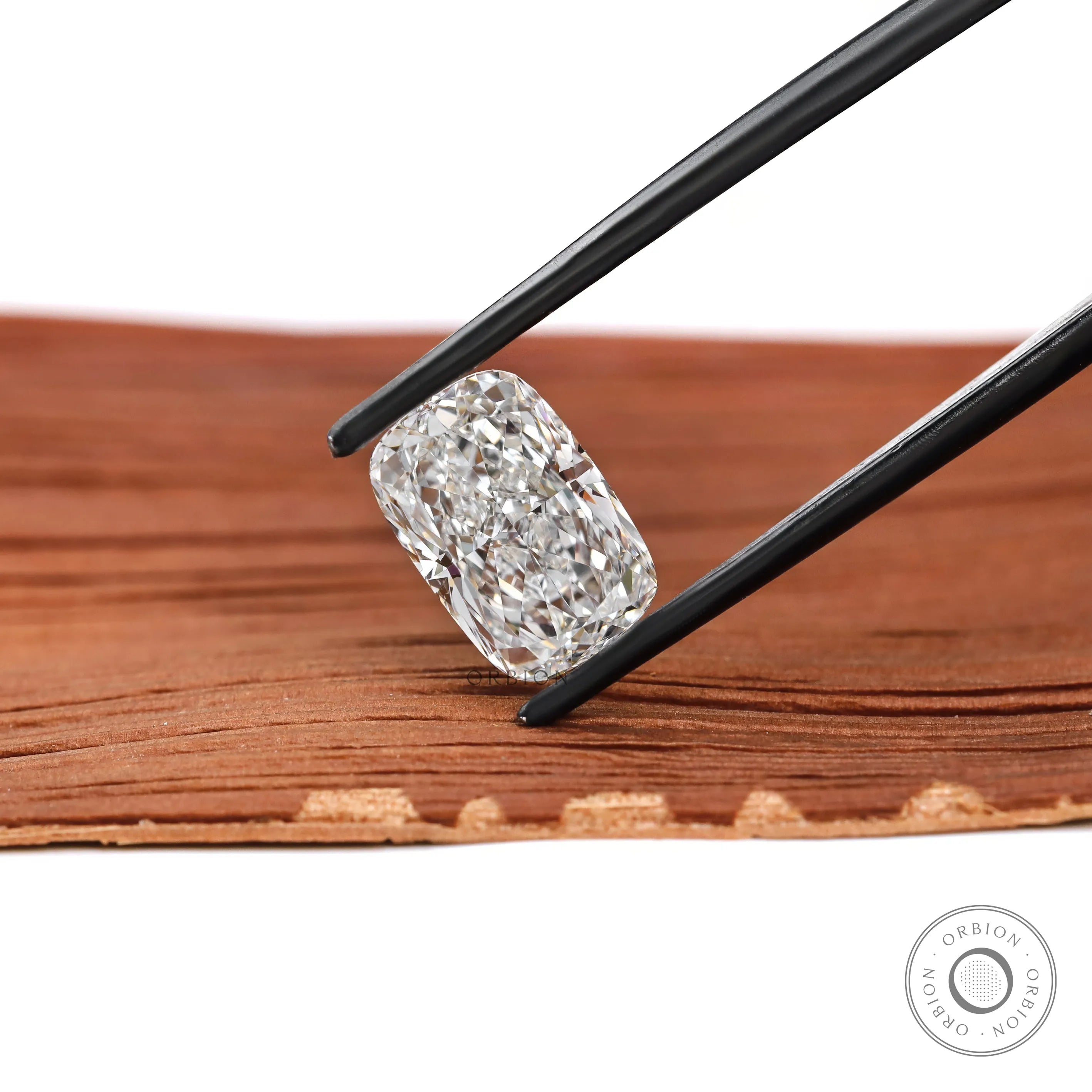 Angled elongated cushion brilliant cut lab diamond in black tweezers