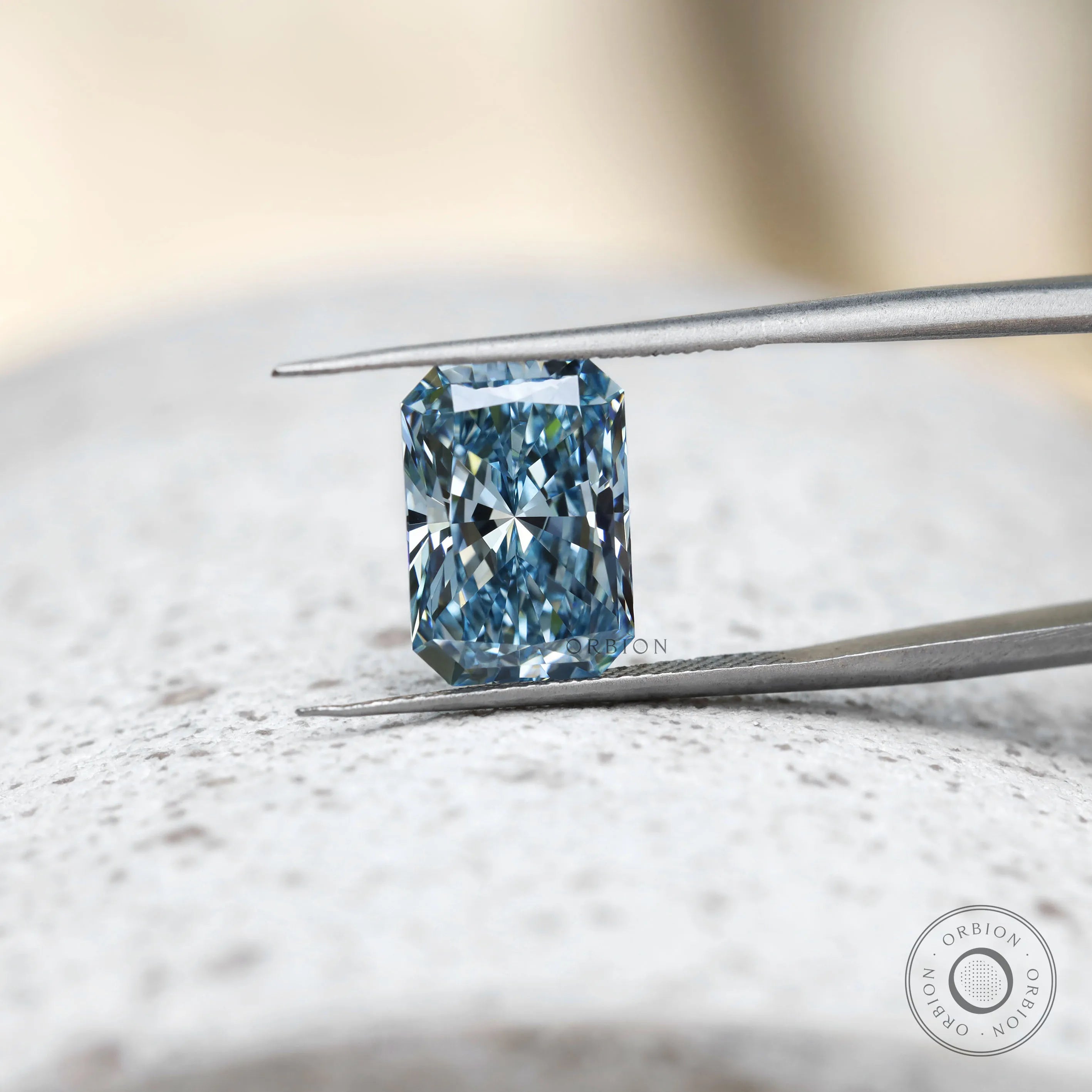 Radiant cut blue lab diamond shown upright in tweezers