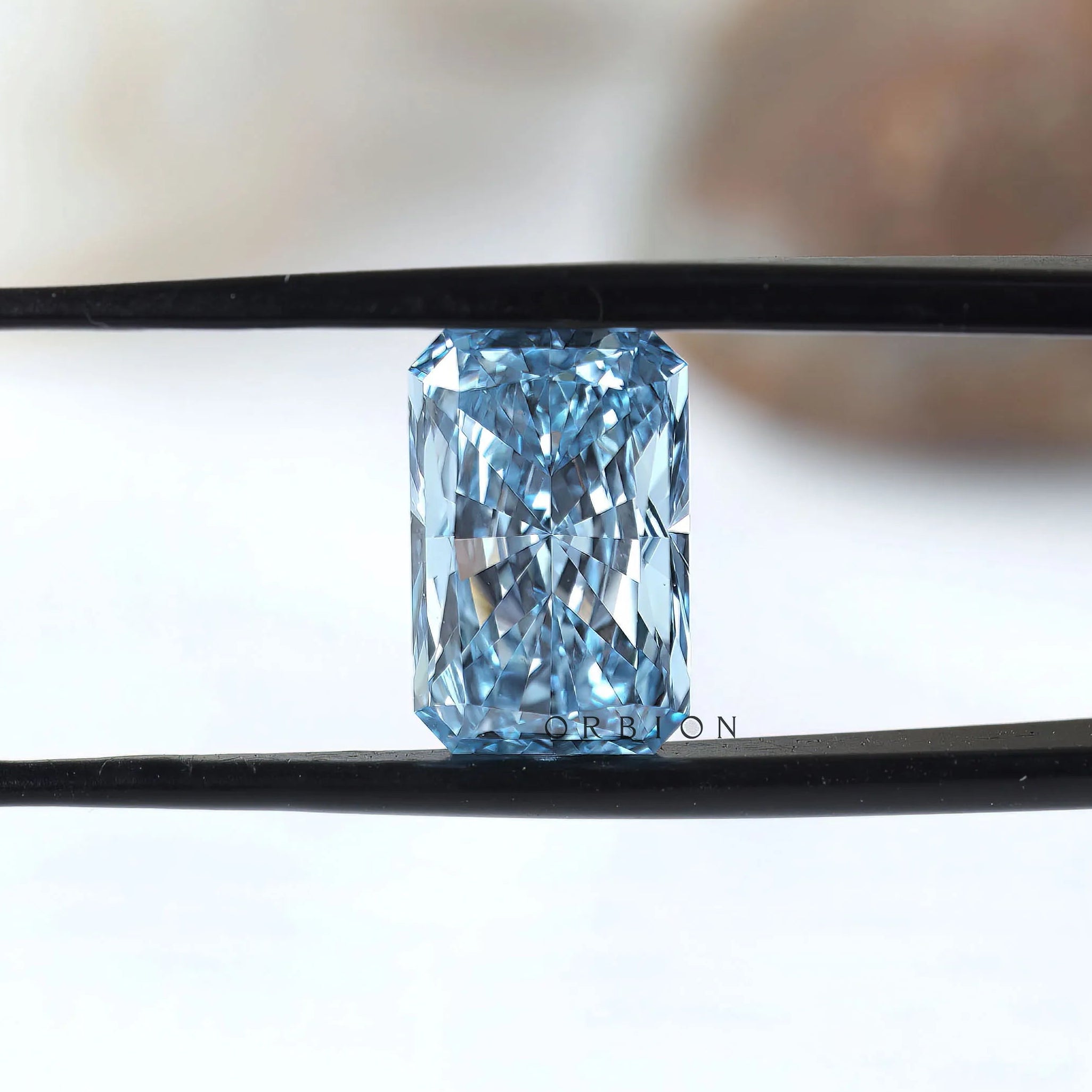 Fancy vivid blue radiant diamond held in black tweezers