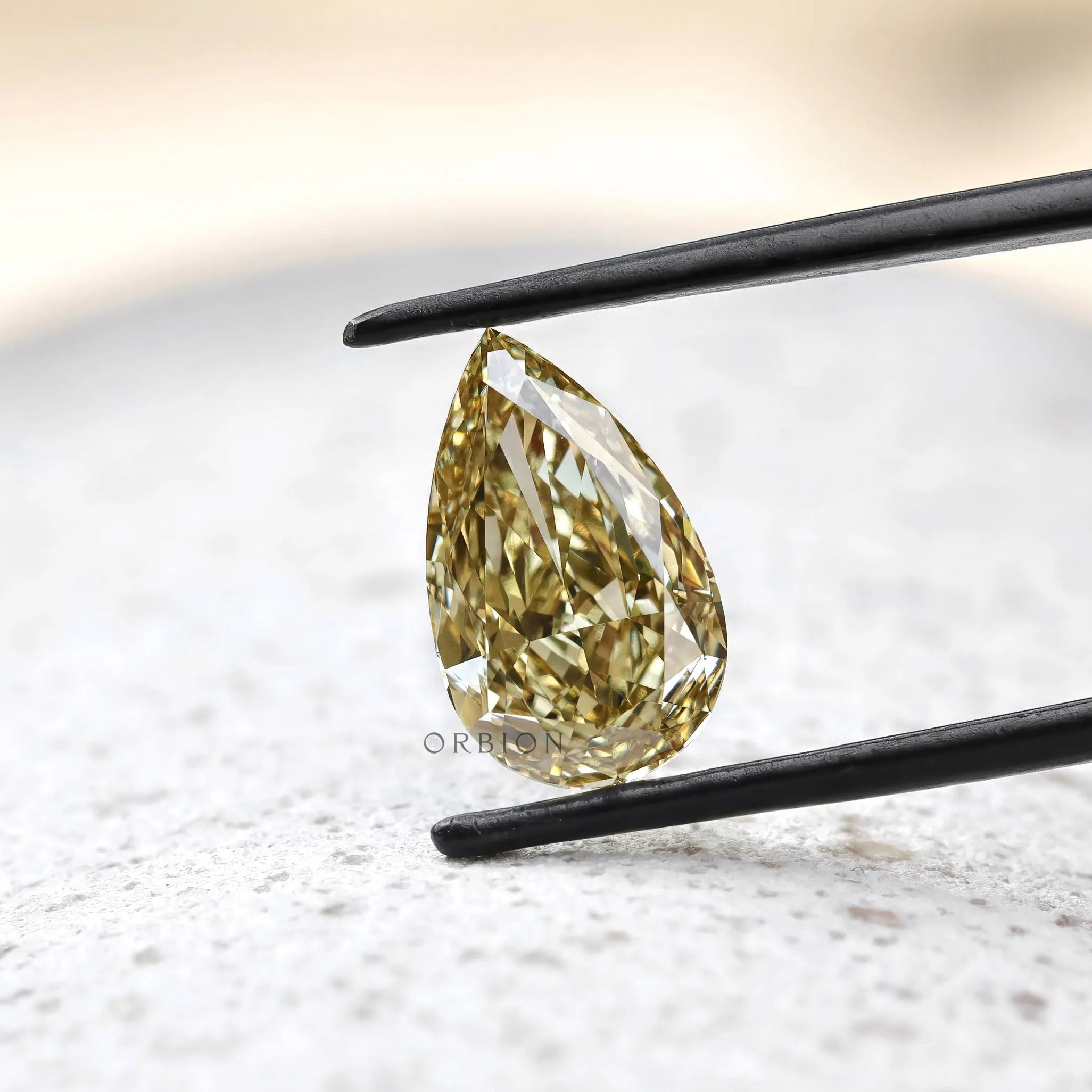 Pear shaped brownish yellow diamond over textured stone surface