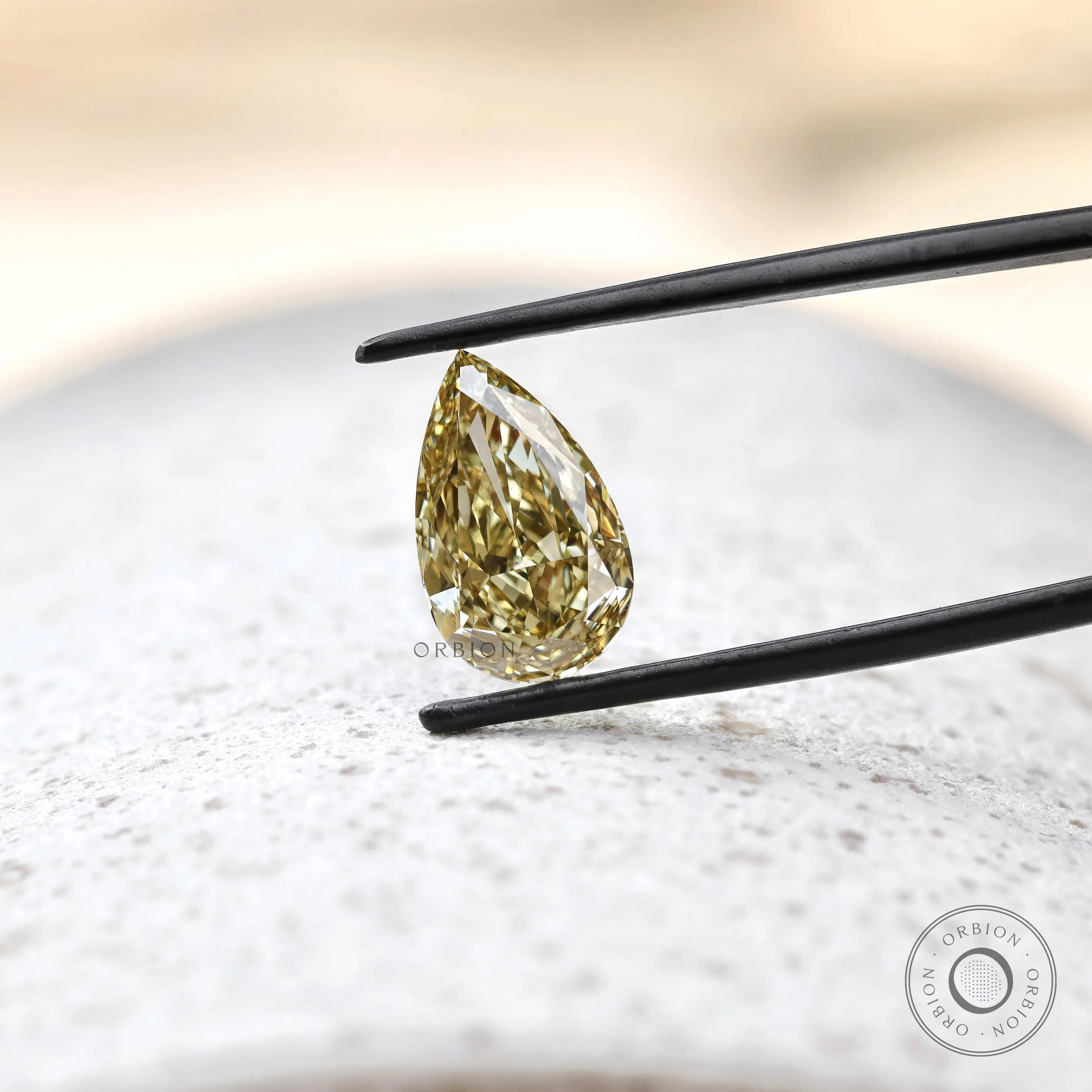 Pear shaped brownish yellow diamond over textured stone surface