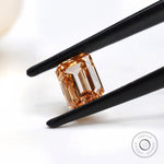 Side angled orange emerald cut diamond in tweezers