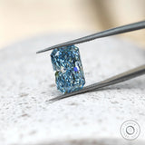 Elongated radiant blue lab diamond angled in silver tweezers