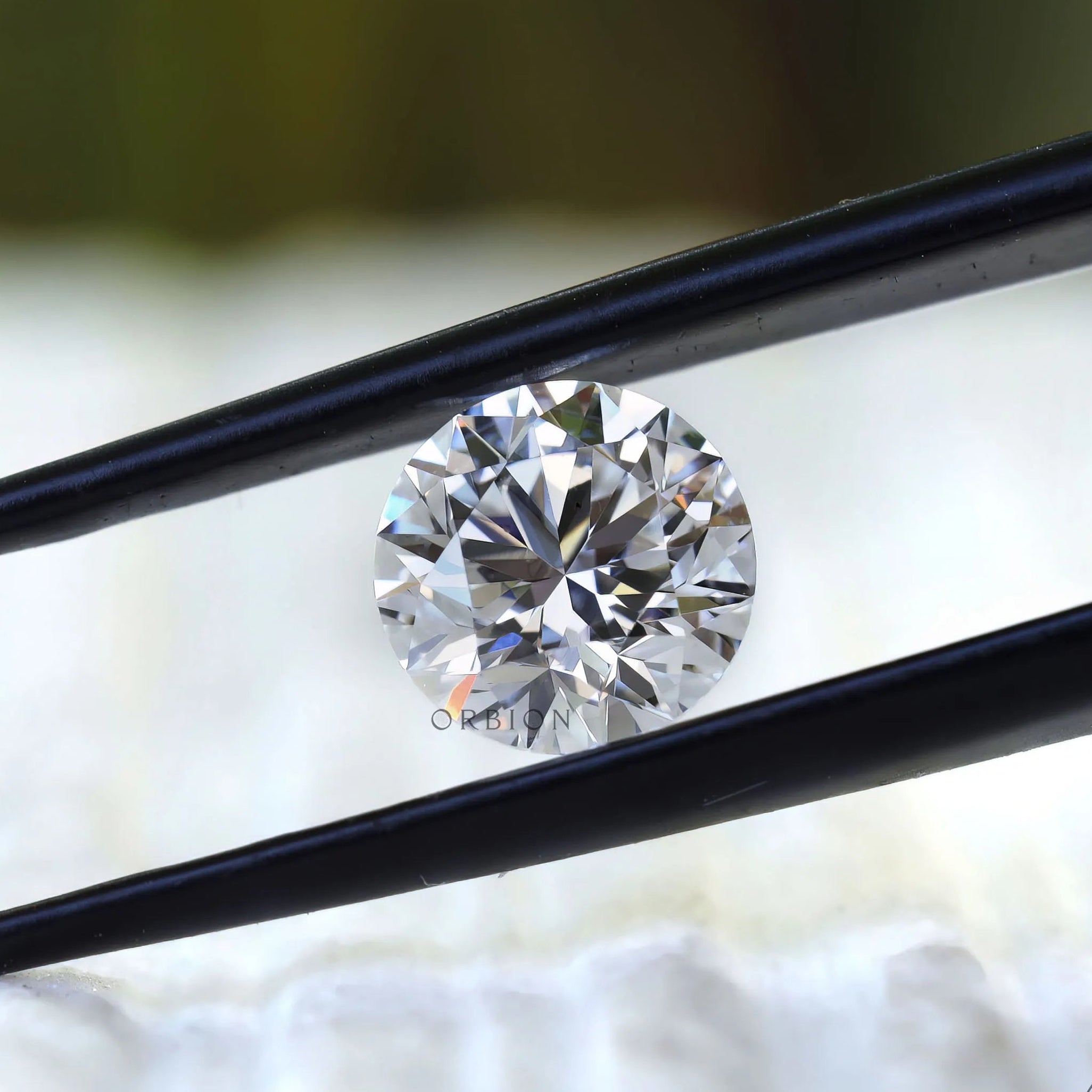 Colorless round diamond centered between tweezers macro view