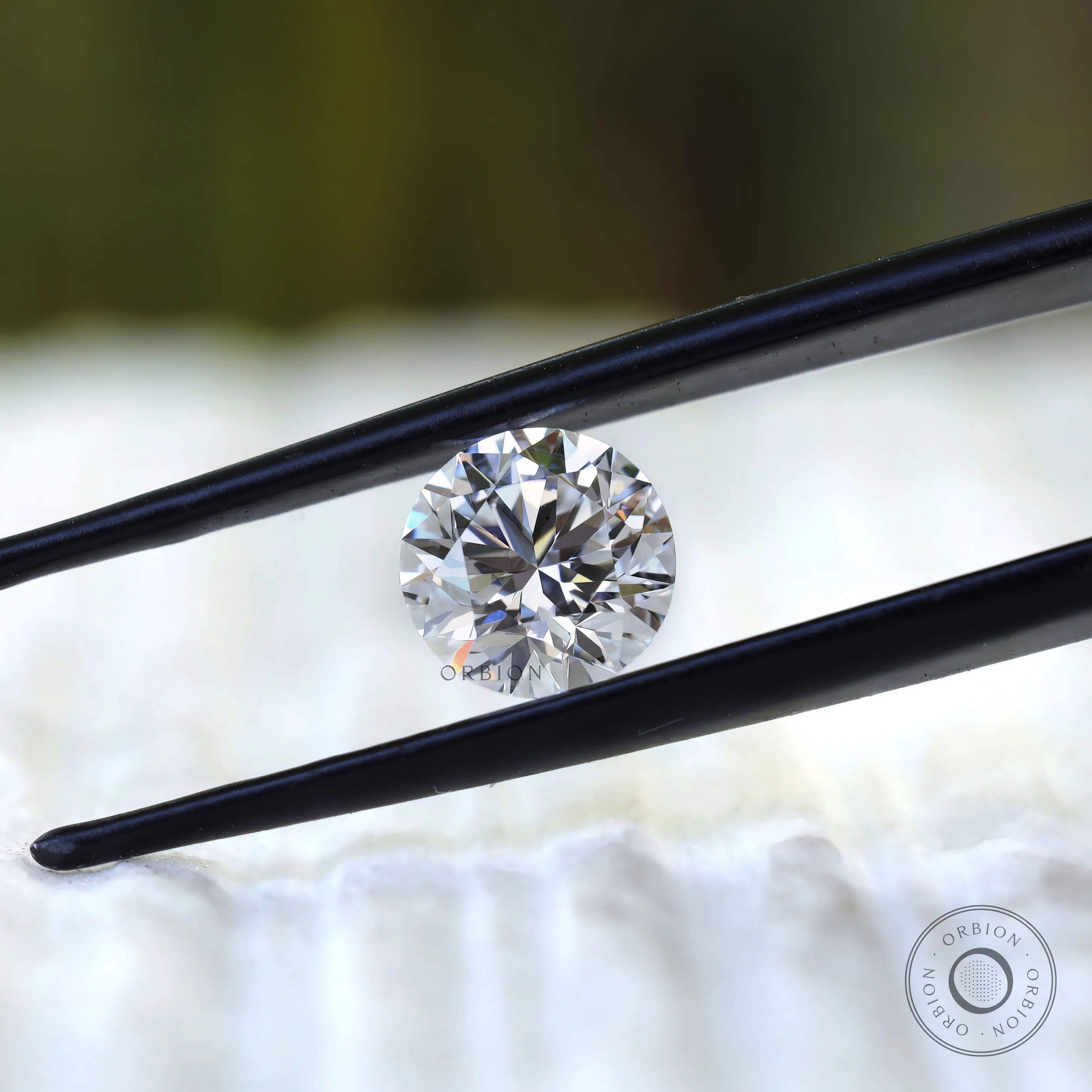 Colorless round diamond centered between tweezers macro view