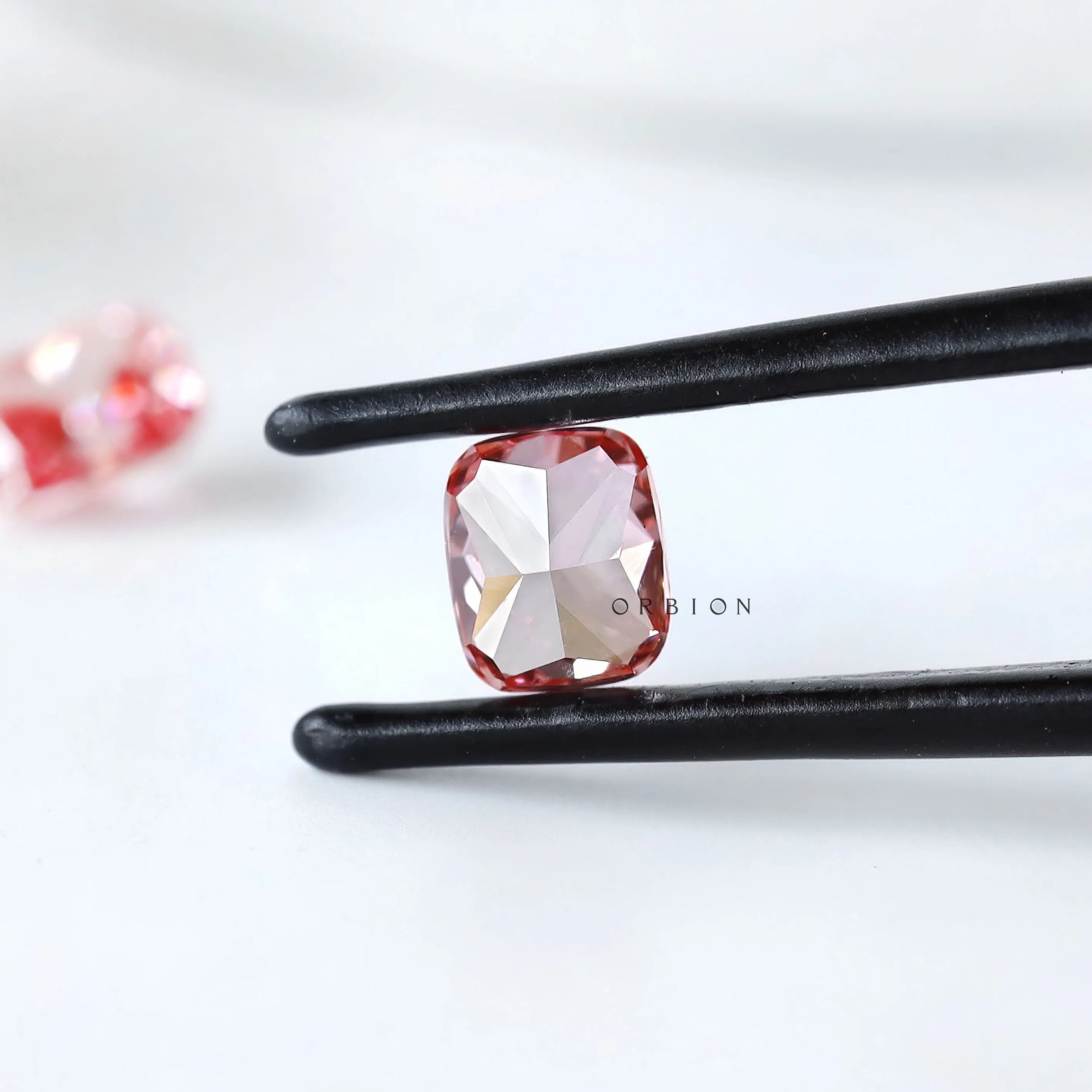 Back view of fancy vivid pink cushion diamond in tweezers